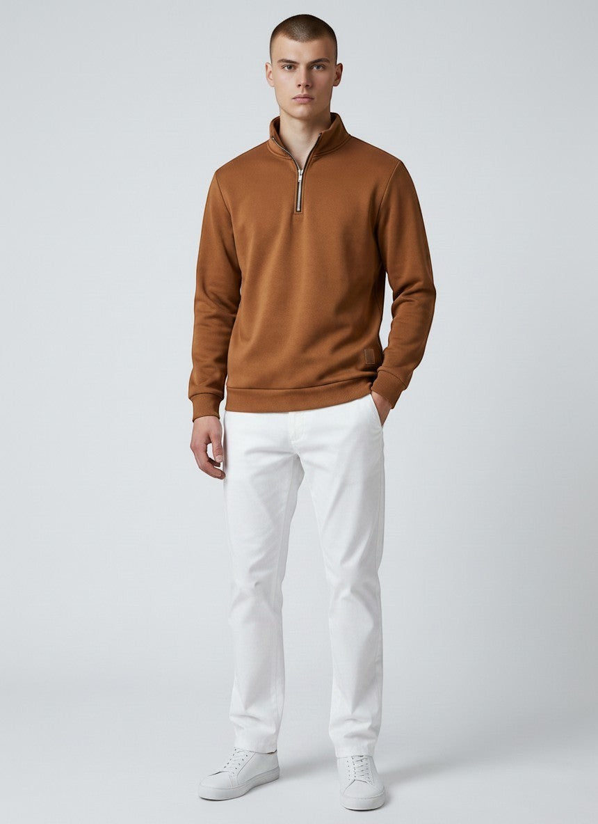 Modelo vestindo blusa Bluviso marrom com zíper no pescoço, gola alta e acabamento canelado, combinada com calça branca.