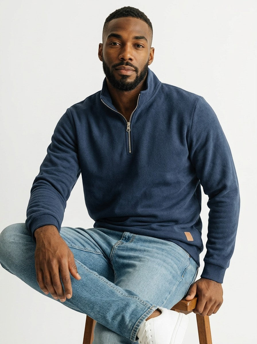 Homem negro vestindo blusa Bluviso azul marinho com zíper no pescoço, gola alta e detalhe em couro sintético, estilo casual.