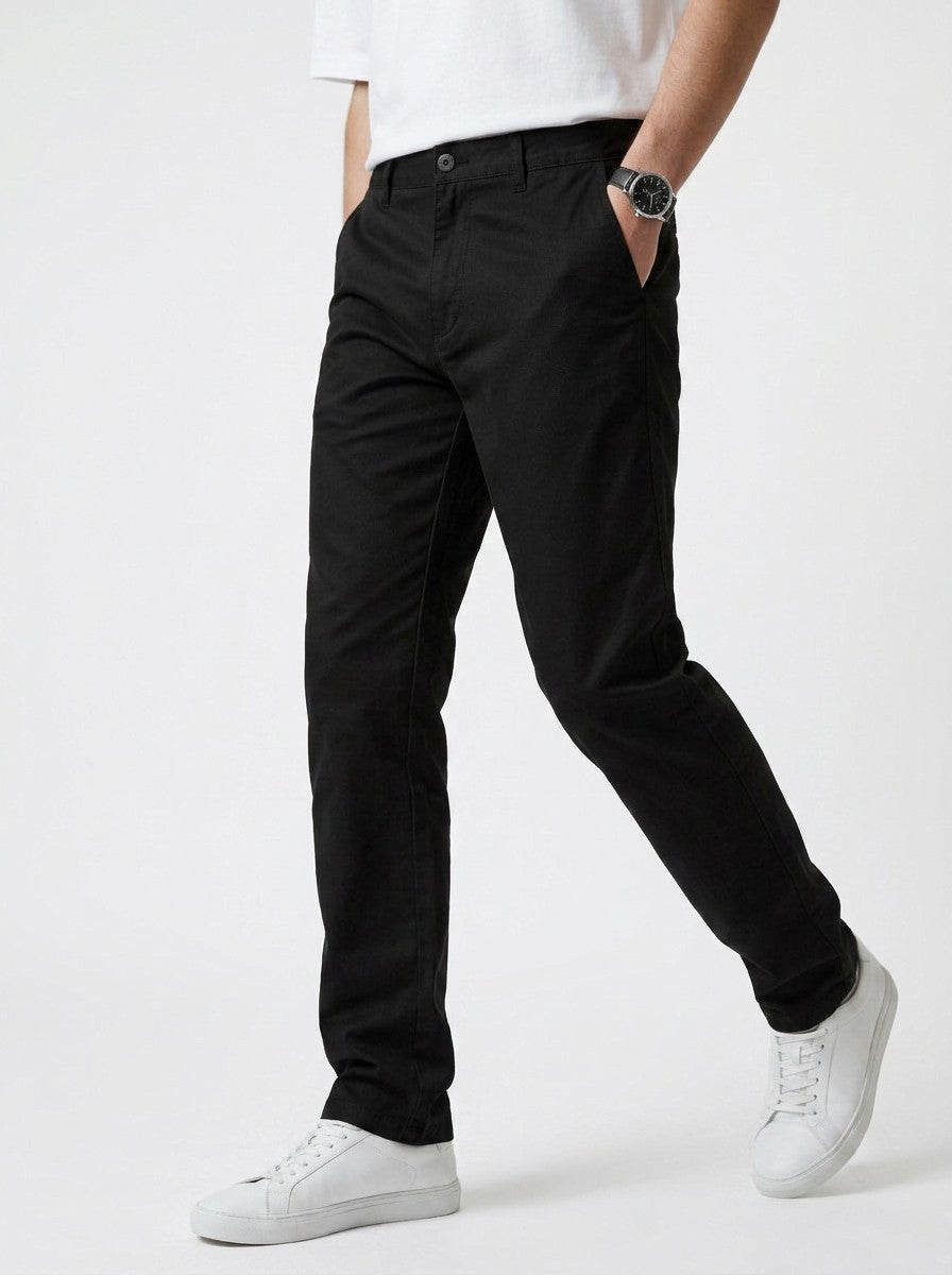 Homem vestindo calça chino em preto Bluviso com camiseta branca e tênis, exibindo corte moderno e ajuste confortável.