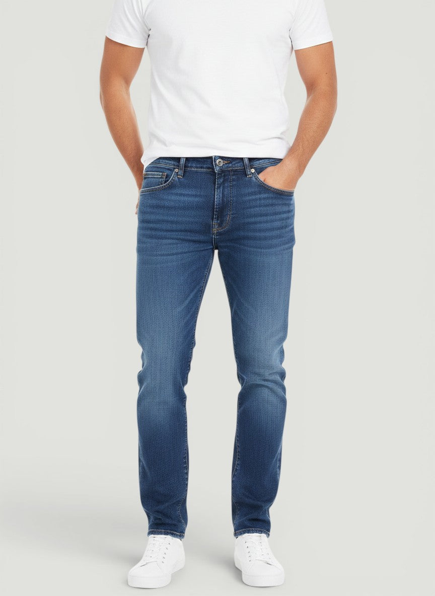 Homem vestindo calça jeans Bluviso azul de corte ajustado com camiseta branca e tênis casual
