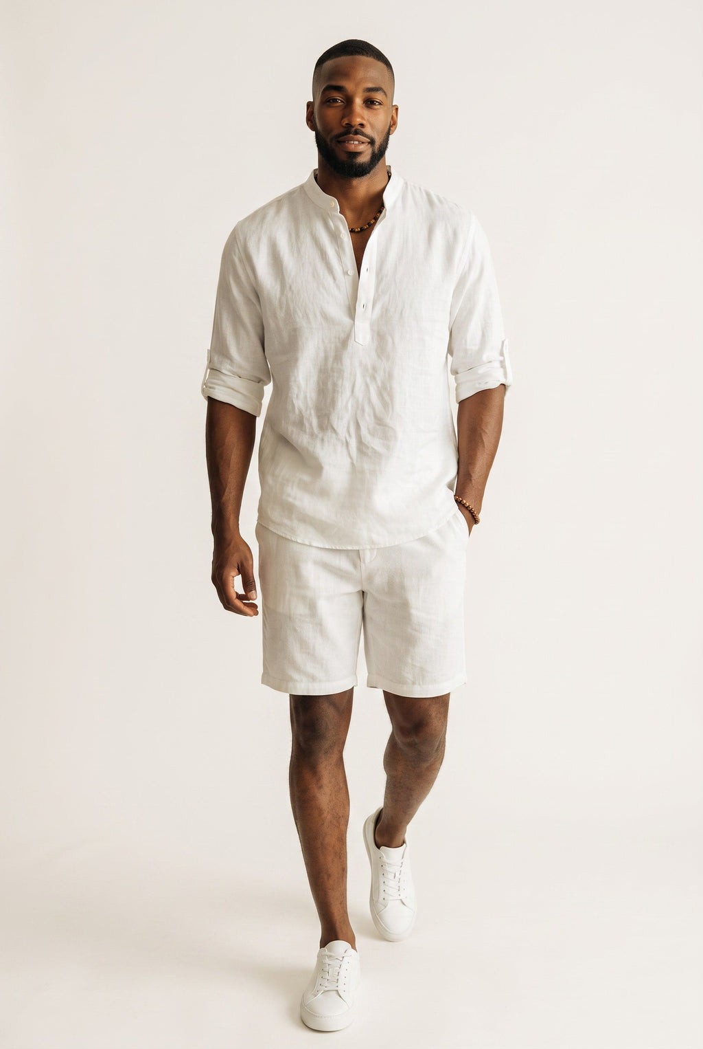 Homem vestindo camisa polo Bluviso de manga longa branca em linho e algodão com gola padre e bermuda combinando