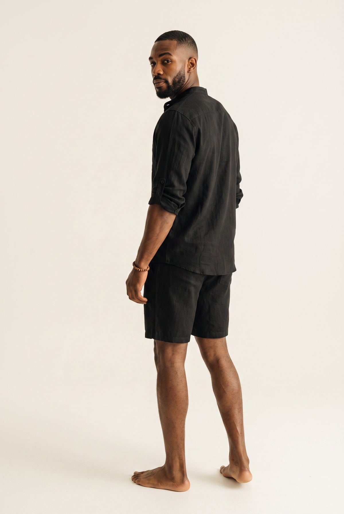 Homem negro vestindo conjunto Bluviso de camisa polo preta de manga longa em linho e algodão com bermuda combinando