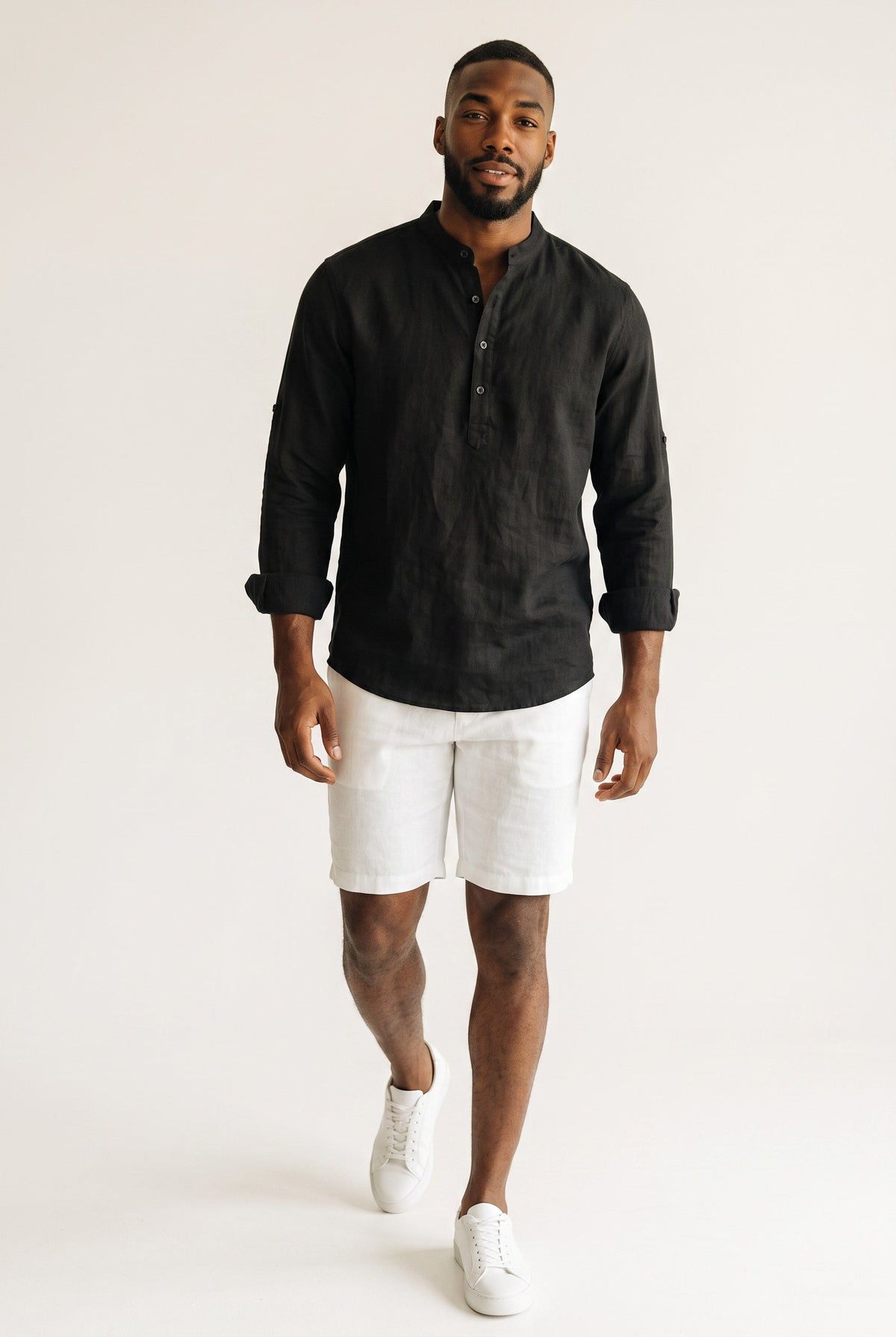 Modelo veste camisa polo Bluviso preta de manga longa em linho e algodão com gola padre e bermuda branca casual