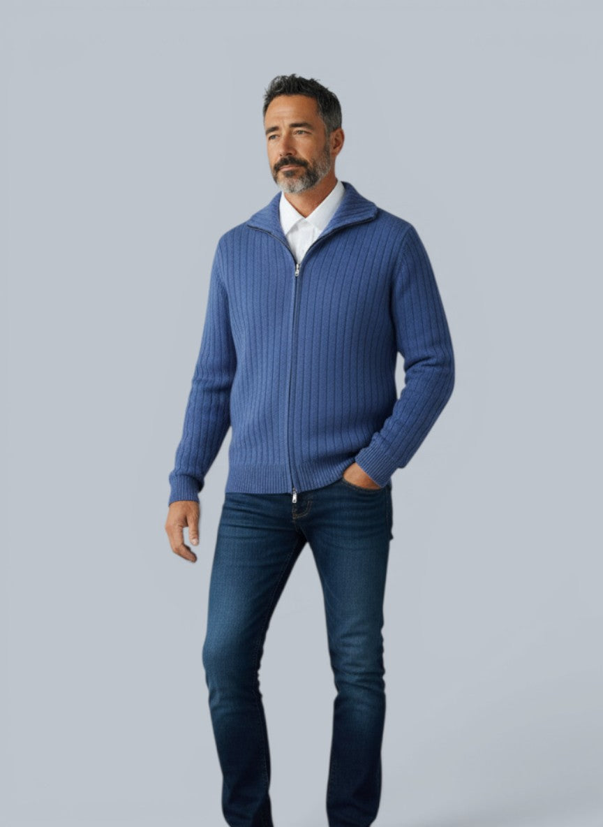 Homem vestindo cardigã de lã merino azul claro com zíper e gola alta da marca Bluviso, combinado com jeans e tênis branco.