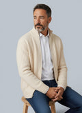 Cardigã masculino de lã merino bege com gola alta e zíper, da marca Bluviso, usado sobre camisa social branca.