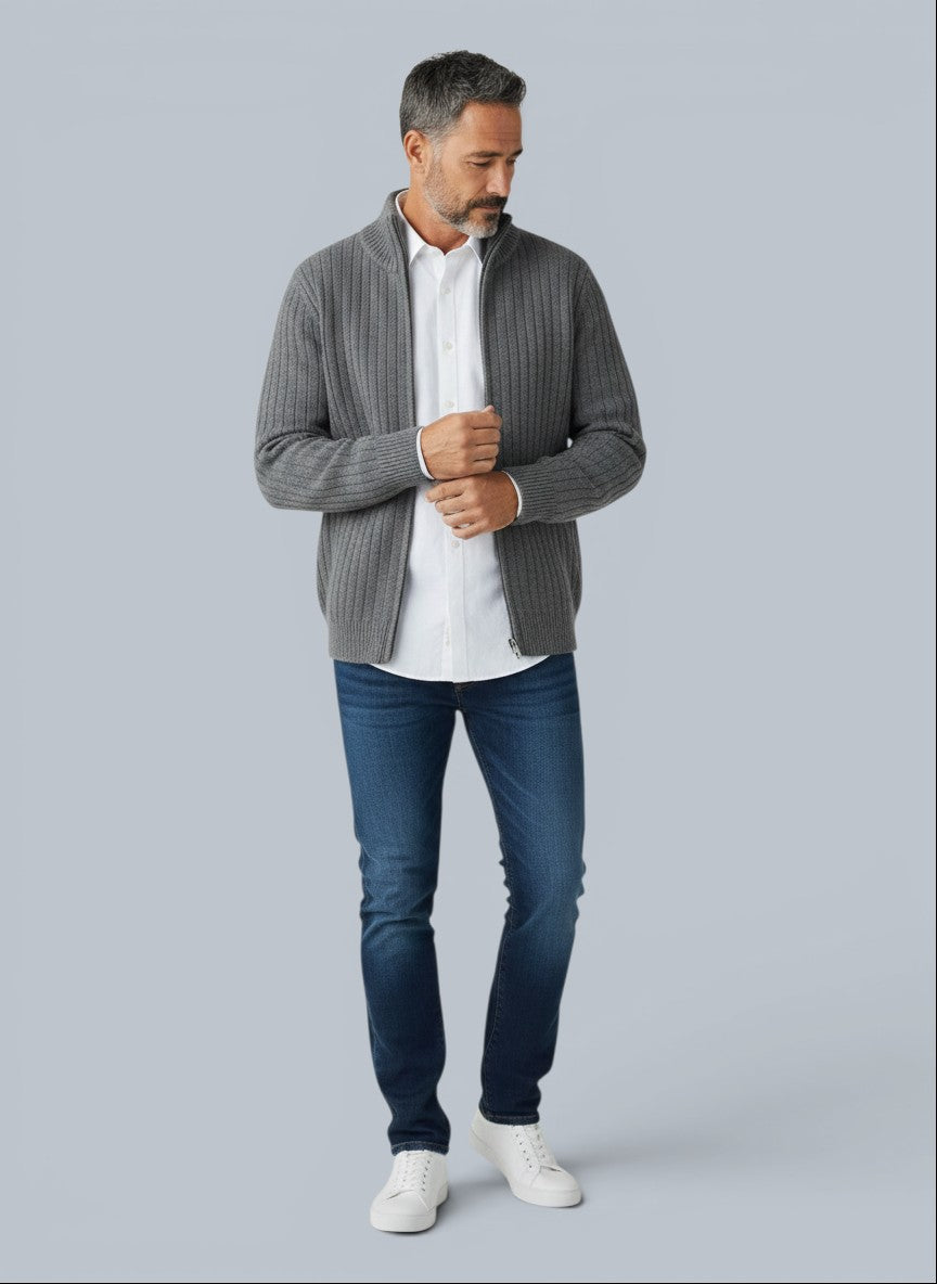 Homem vestindo cardigã cinza de lã merino com zíper e gola alta da marca Bluviso sobre camisa branca e jeans.