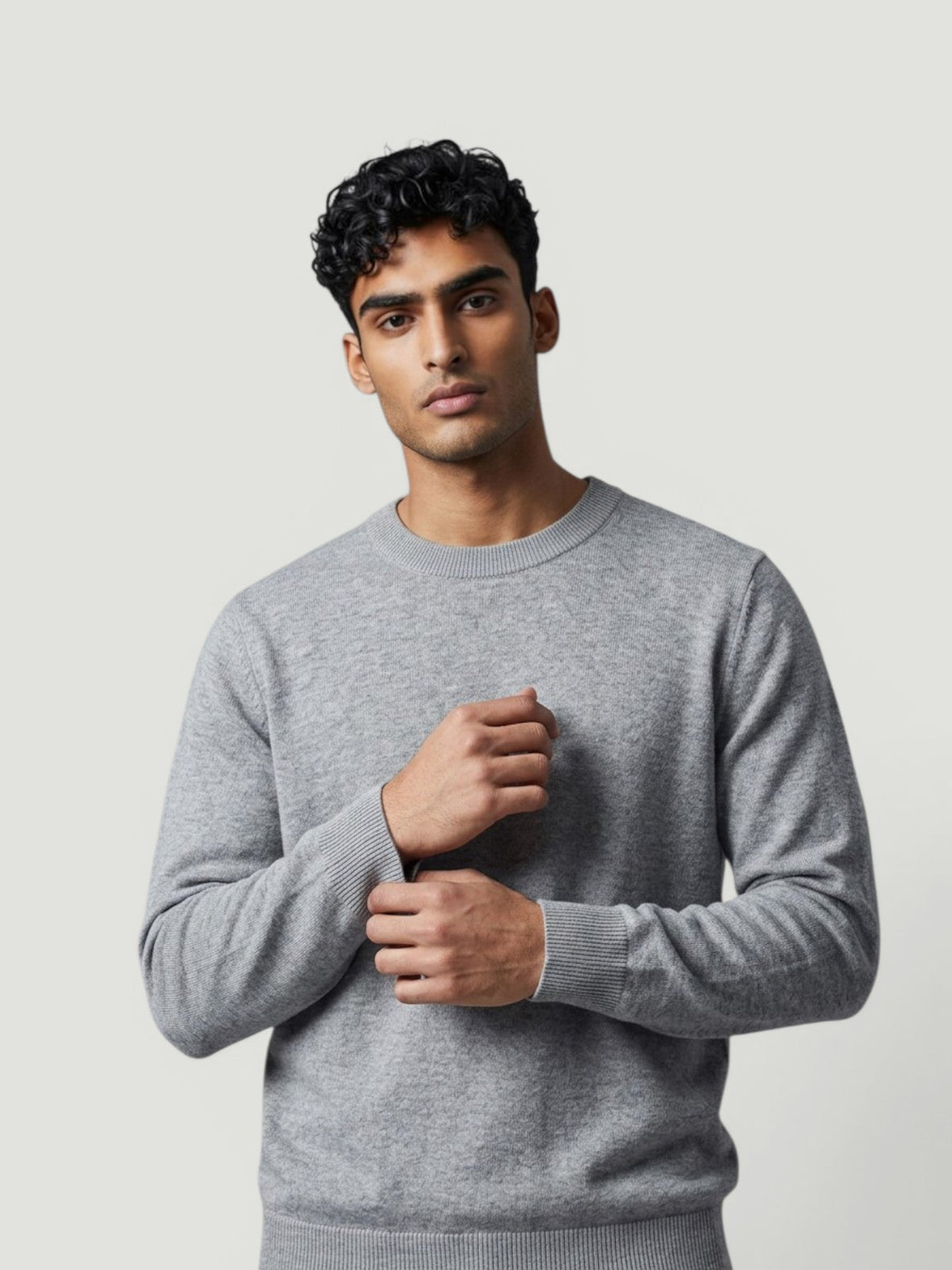 Homem vestindo suéter de tricô cinza claro Bluviso com gola careca, estilo casual e elegante em fundo neutro.