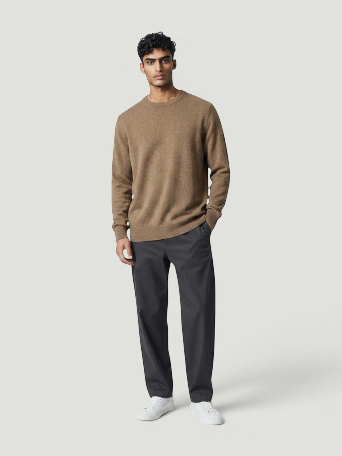 Modelo vestindo suéter de tricô na cor bege com gola careca Bluviso, combinado com calça cinza e tênis branco.