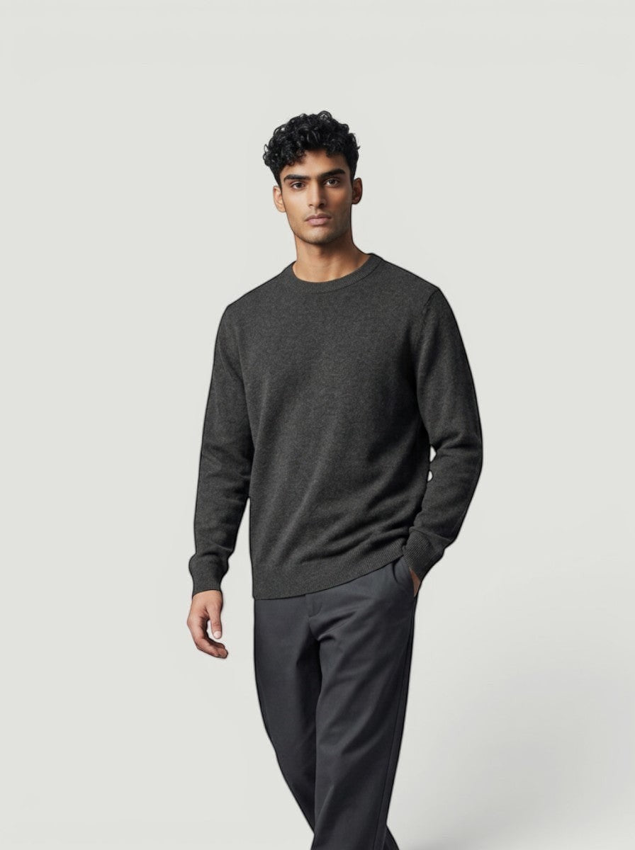 Modelo vestindo suéter de tricô cinza escuro com gola careca da Bluviso, combinado com calça social e tênis branco.